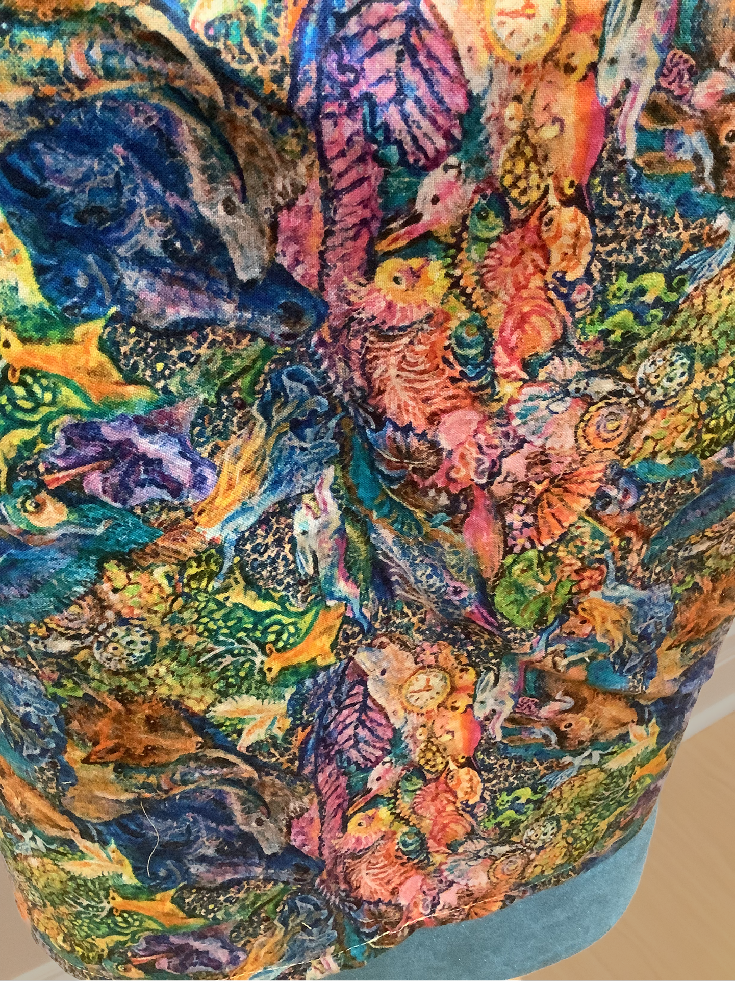 Close up of the print on a tank top. The print is rainbow colored and features forest animals and leaves.